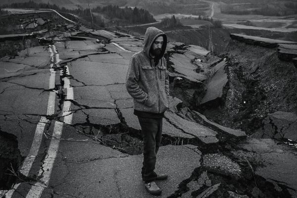 Man standing on a road destroyed by an earthquake. How to help victims of the earthquakes in Turkey and Syria